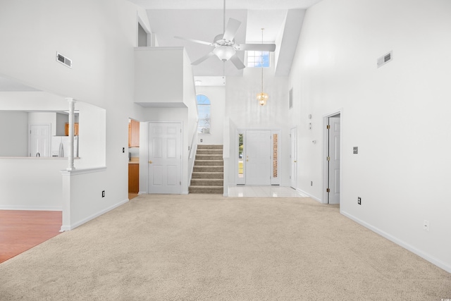 unfurnished living room with carpet floors, a high ceiling, ceiling fan, stairs, and baseboards