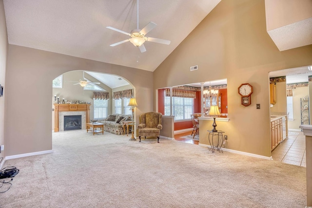 carpeted living room featuring ceiling fan with notable chandelier and high vaulted ceiling