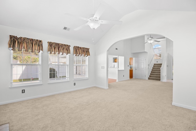 spare room with a ceiling fan, arched walkways, light carpet, stairway, and plenty of natural light
