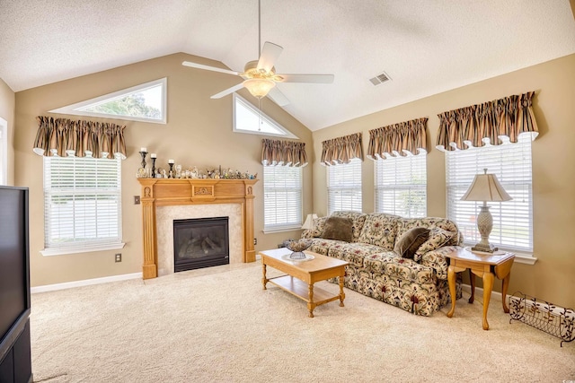 living room with carpet, ceiling fan, lofted ceiling, and a tiled fireplace