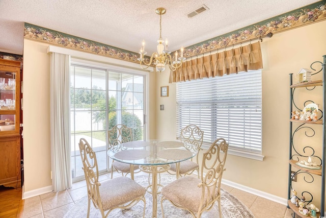 tiled dining room featuring a textured ceiling and a notable chandelier