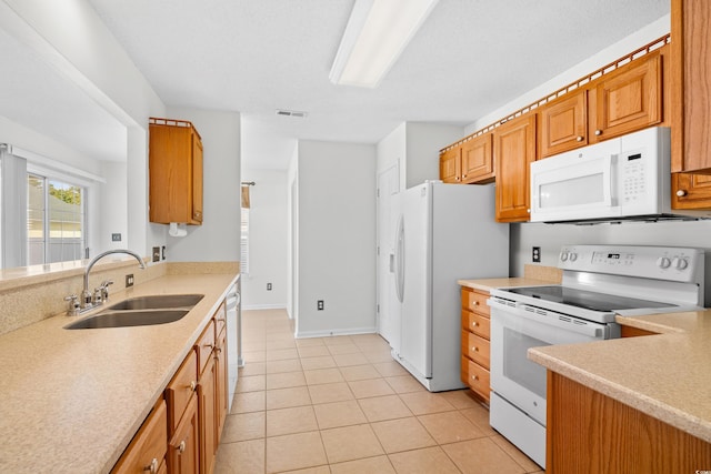 kitchen featuring white appliances, a sink, light countertops, and light tile patterned flooring