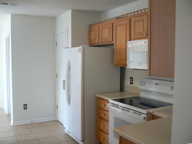 kitchen featuring a textured ceiling, white appliances, and light tile patterned floors