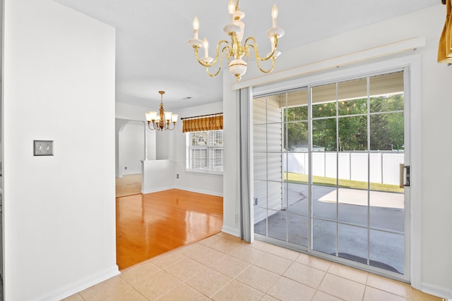 unfurnished dining area featuring a chandelier, baseboards, and light tile patterned floors