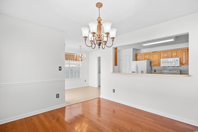unfurnished dining area featuring a chandelier, wood finished floors, and baseboards