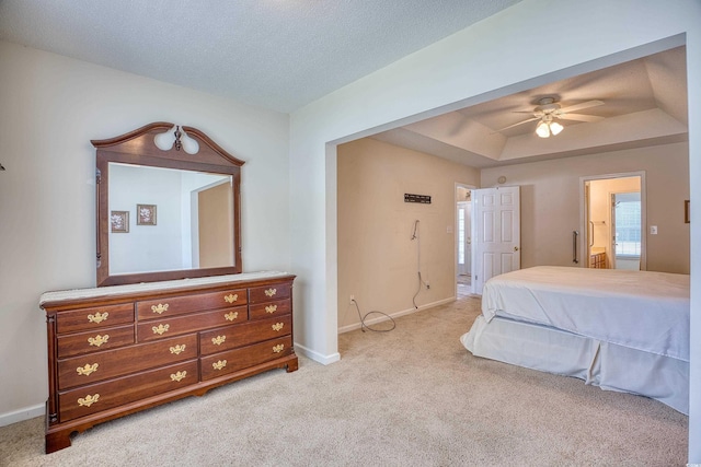 carpeted bedroom featuring a textured ceiling, ceiling fan, a raised ceiling, and ensuite bathroom