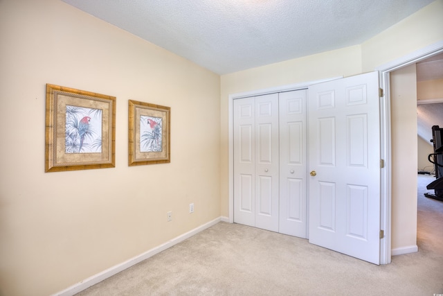 unfurnished bedroom with a textured ceiling, light carpet, and a closet