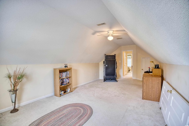 additional living space featuring a textured ceiling, ceiling fan, light carpet, and vaulted ceiling