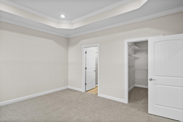 unfurnished bedroom with connected bathroom, a spacious closet, light carpet, a closet, and ornamental molding