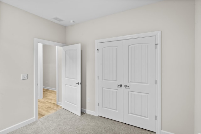 unfurnished bedroom featuring light carpet and a closet