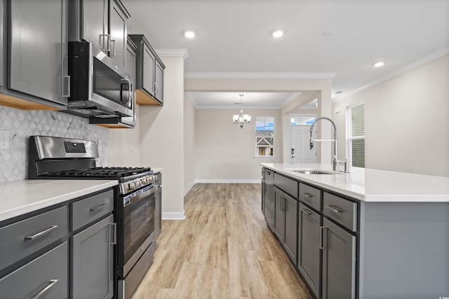 kitchen with sink, stainless steel appliances, an inviting chandelier, decorative backsplash, and light wood-type flooring