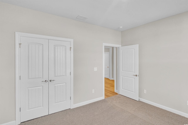 unfurnished bedroom featuring light colored carpet and a closet