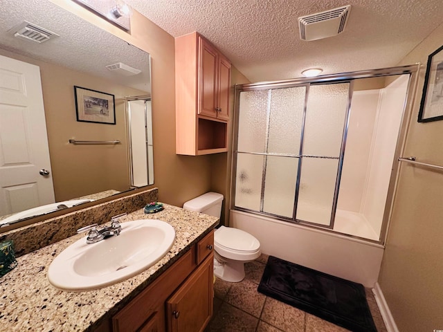 full bathroom with a textured ceiling, tile floors, bath / shower combo with glass door, vanity, and toilet