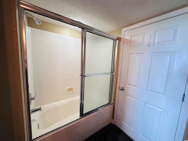 bathroom featuring enclosed tub / shower combo and a textured ceiling