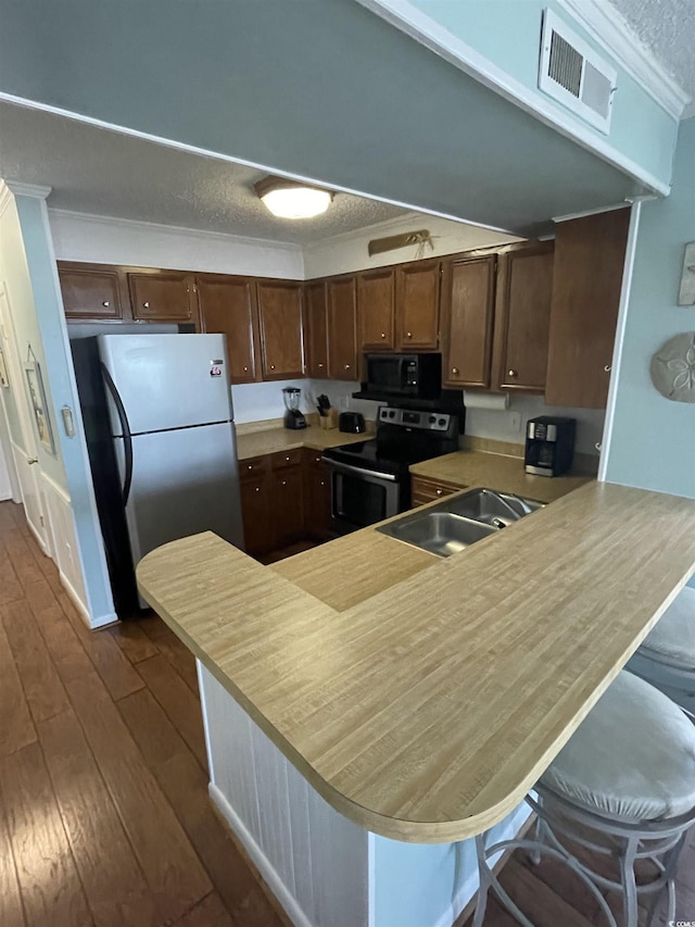 kitchen featuring kitchen peninsula, stainless steel appliances, dark hardwood / wood-style flooring, a textured ceiling, and sink