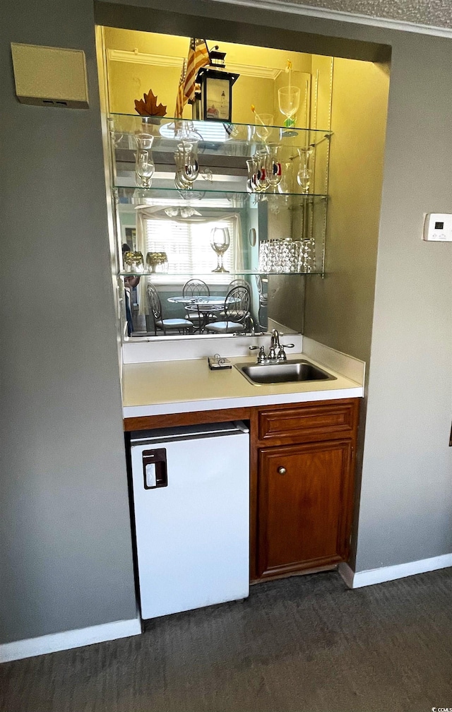 bar with dark wood-type flooring, sink, and dishwashing machine