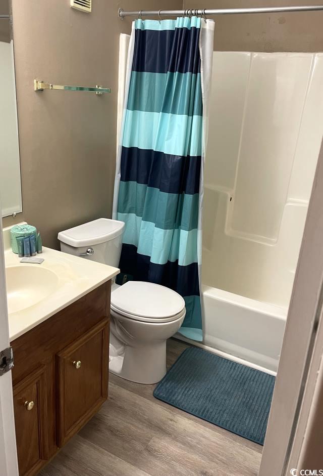 full bathroom featuring toilet, hardwood / wood-style floors, vanity, and shower / bath combo with shower curtain