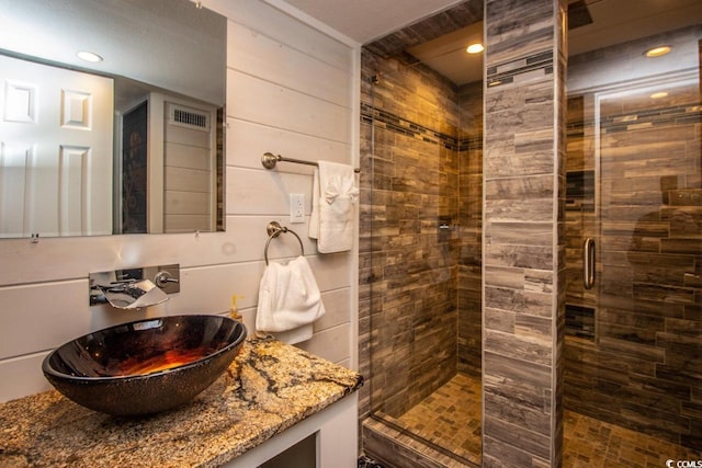 bathroom with a shower with shower door and vanity