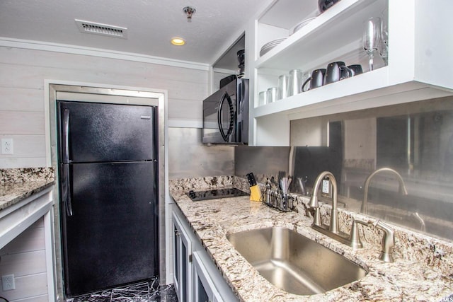 kitchen with black appliances, sink, and light stone counters