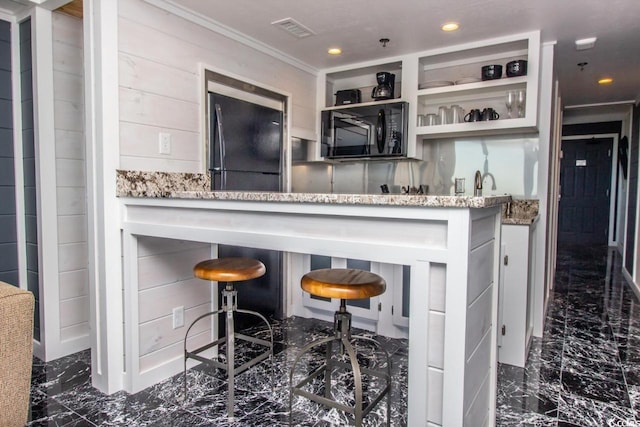 kitchen with crown molding, light stone countertops, refrigerator, and dark tile floors