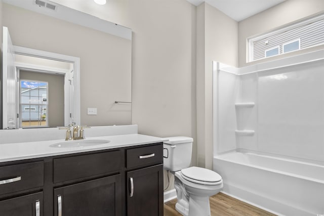full bathroom featuring a wealth of natural light, hardwood / wood-style floors, vanity, and toilet