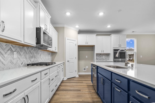 kitchen featuring hardwood / wood-style floors, blue cabinets, ornamental molding, white cabinetry, and stainless steel appliances