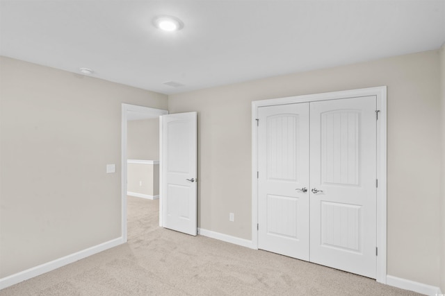 unfurnished bedroom featuring a closet and light colored carpet