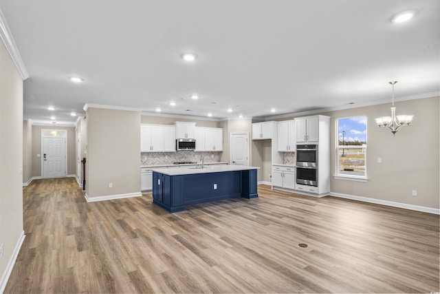 kitchen with light hardwood / wood-style floors, crown molding, white cabinetry, and stainless steel appliances