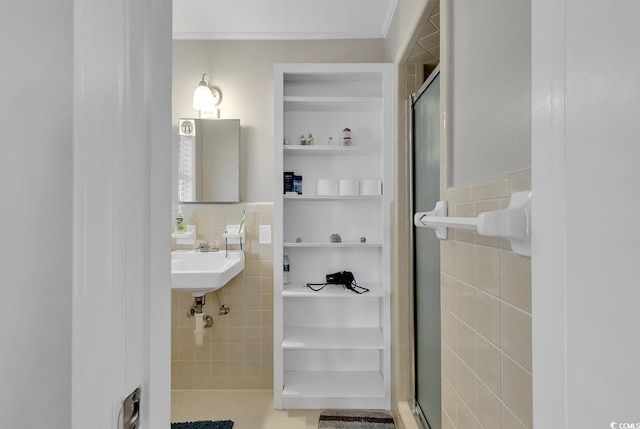 bathroom featuring tile walls, tasteful backsplash, tile floors, a shower with shower door, and sink