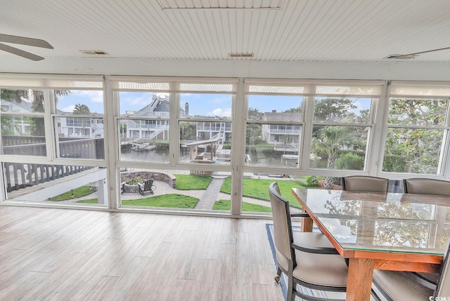 unfurnished sunroom with a wealth of natural light, a water view, and ceiling fan