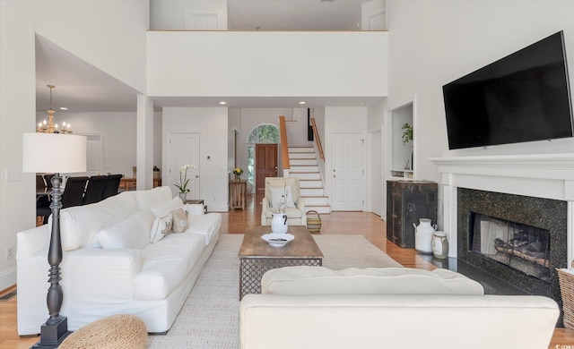 living room with light hardwood / wood-style floors, a high ceiling, and a chandelier