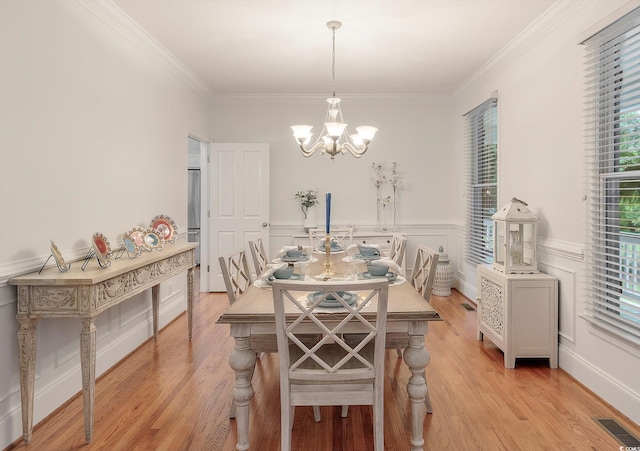 dining space with light hardwood / wood-style floors, a notable chandelier, and ornamental molding