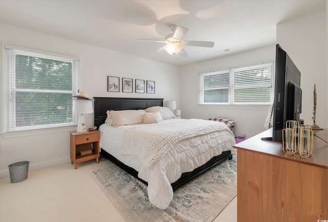 bedroom featuring light carpet, multiple windows, and ceiling fan