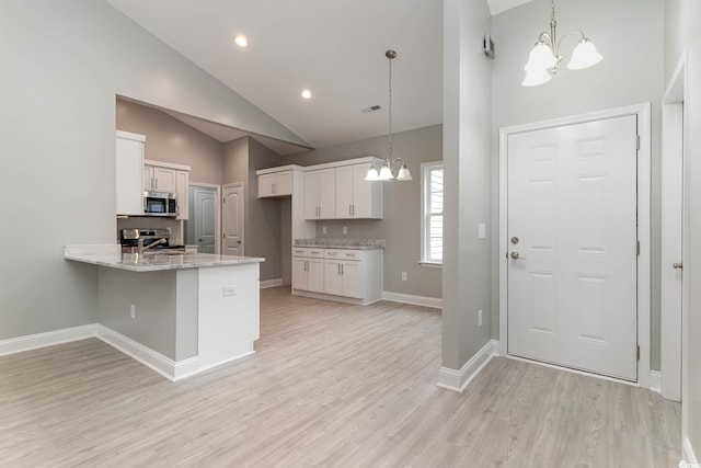 kitchen featuring white cabinetry, hanging light fixtures, appliances with stainless steel finishes, and an inviting chandelier