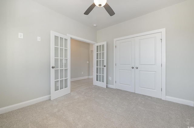 unfurnished bedroom featuring ceiling fan, a closet, light carpet, and french doors