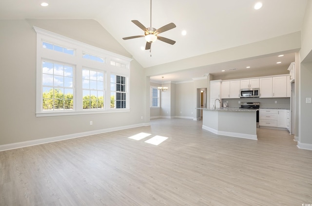 interior space with ceiling fan with notable chandelier, light hardwood / wood-style floors, high vaulted ceiling, and sink