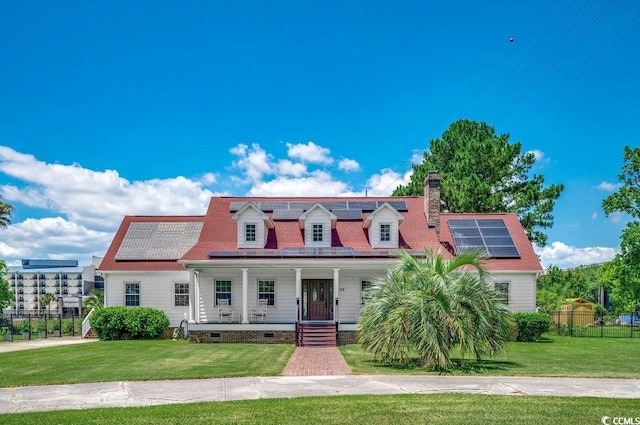 cape cod house with covered porch, a front yard, and solar panels