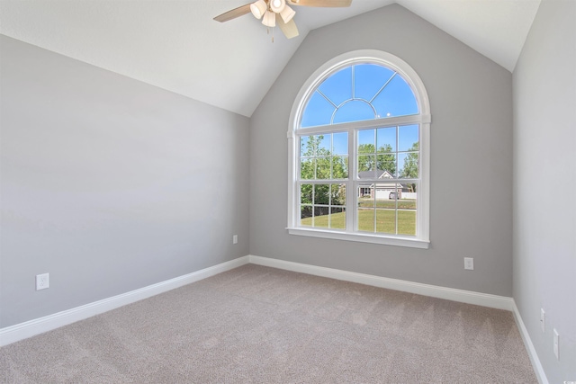 carpeted spare room featuring ceiling fan, vaulted ceiling, and a wealth of natural light