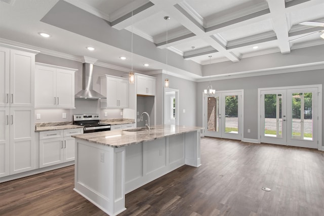 kitchen with a center island with sink, wall chimney exhaust hood, stainless steel range with electric stovetop, and white cabinetry