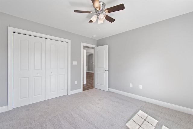 unfurnished bedroom featuring ceiling fan, a closet, and light carpet