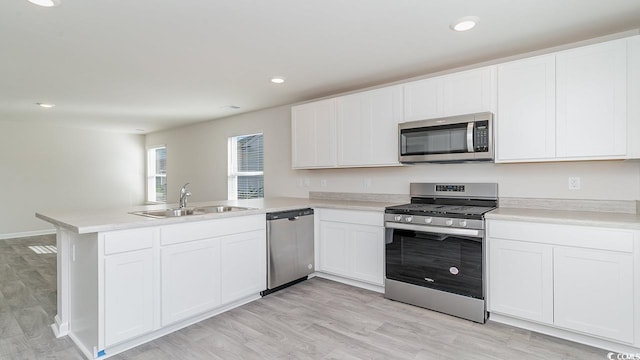 kitchen featuring light countertops, appliances with stainless steel finishes, a peninsula, white cabinetry, and a sink