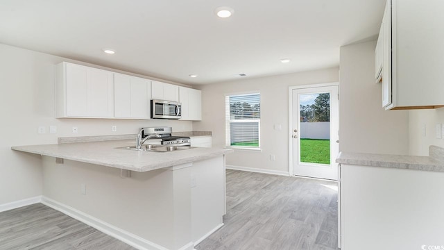 kitchen featuring a sink, stainless steel appliances, light wood-style floors, and light countertops