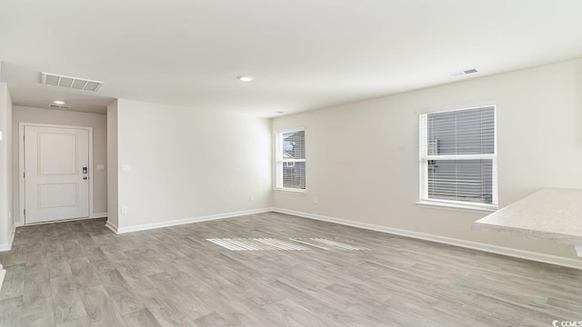 unfurnished room with baseboards, visible vents, and light wood-type flooring