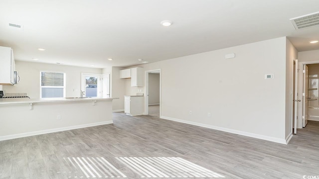 unfurnished living room featuring visible vents, baseboards, and light wood-style flooring