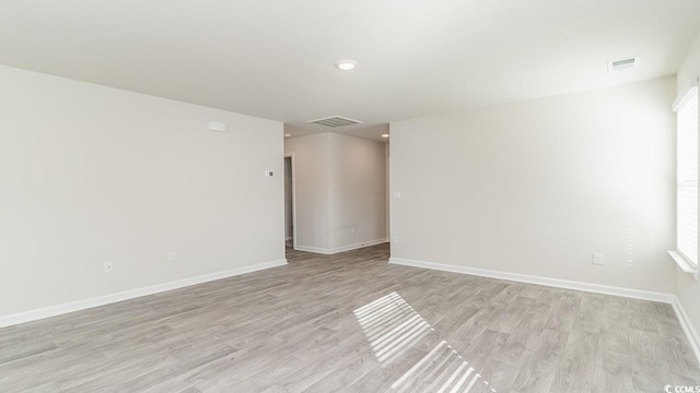 empty room featuring visible vents, baseboards, plenty of natural light, and light wood finished floors