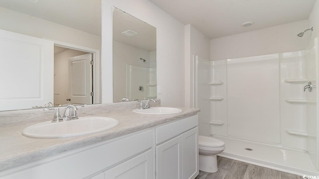 bathroom featuring toilet, a shower, and a sink