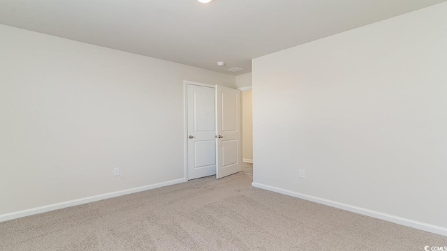 spare room featuring baseboards and light carpet