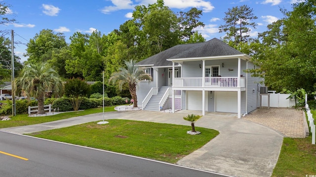 coastal home featuring a porch, a front lawn, and a garage