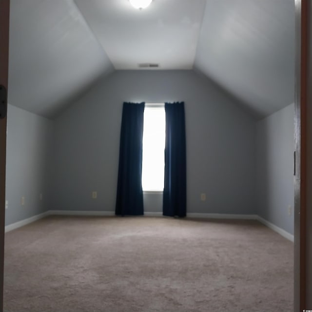 additional living space featuring carpet flooring and vaulted ceiling