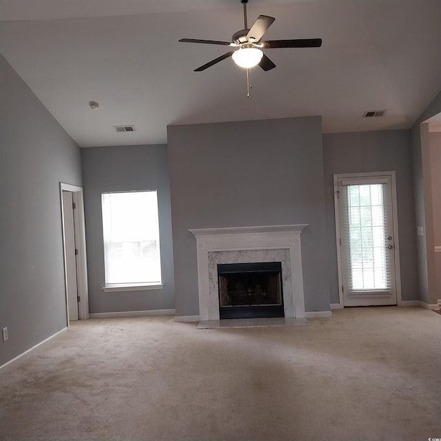 unfurnished living room with a premium fireplace, light colored carpet, ceiling fan, and vaulted ceiling